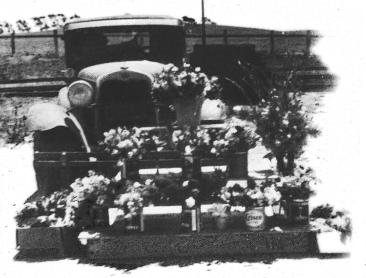 Various flowers on-display in front of a 1940s-era delivery truck